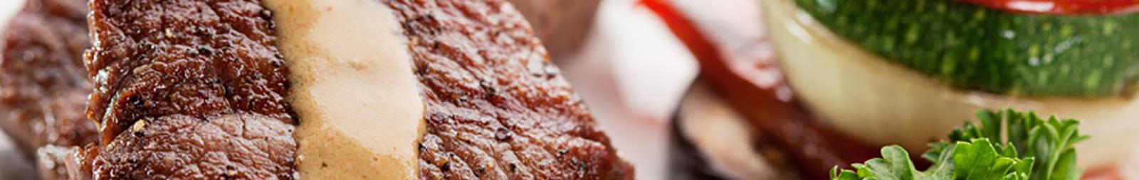 Close up on a steak dressed up with salad and sauce.